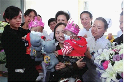 罗丹和尹春林（左）抱着自己的孩子，在医院为两个小家伙组织的出院仪式中接受祝福。 